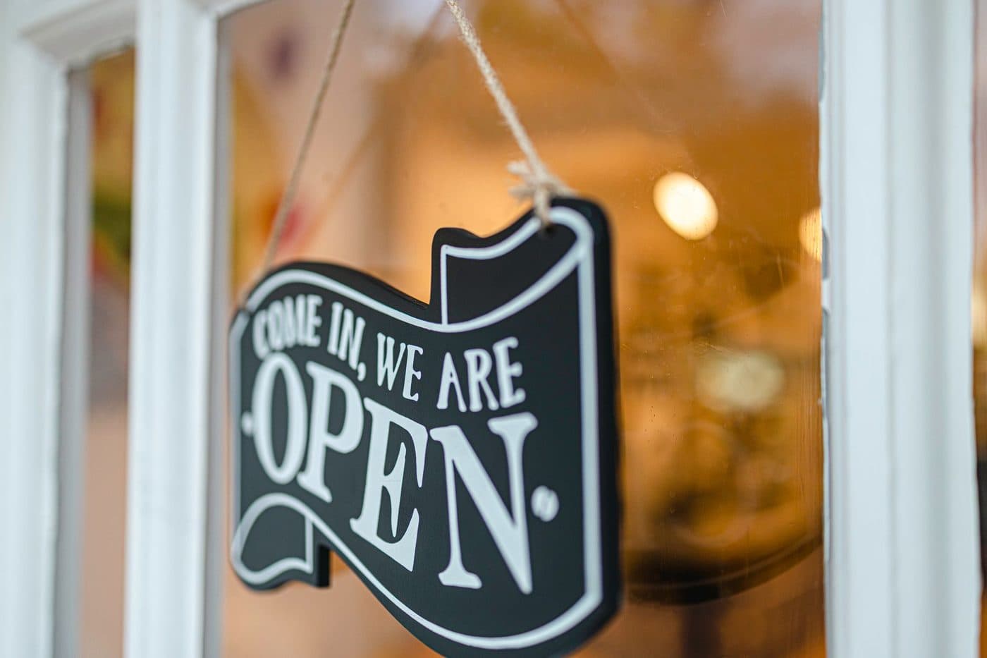 Come in, we are open sign hanging in the glass door of a new business