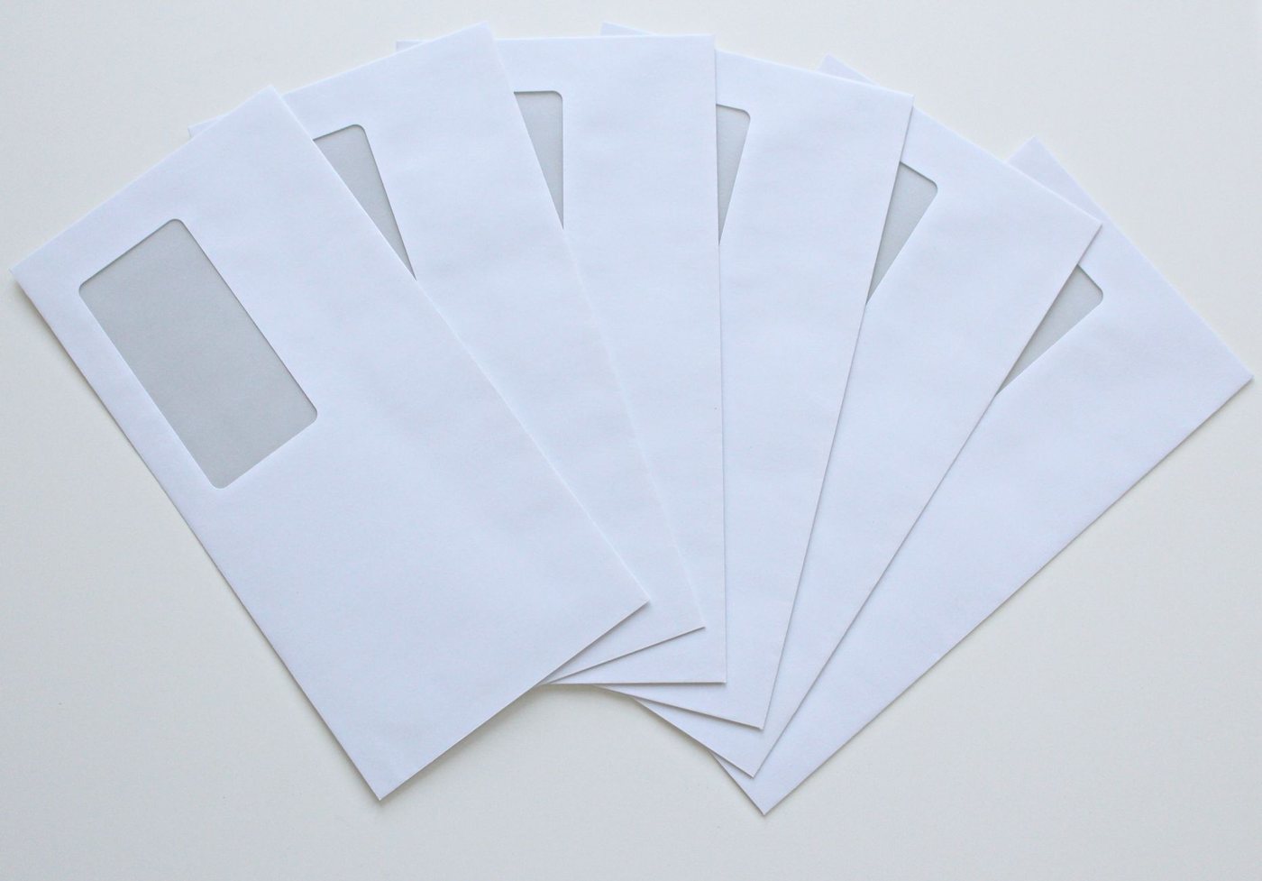 A fan of plain white window envelopes spread across a flat neutral surface