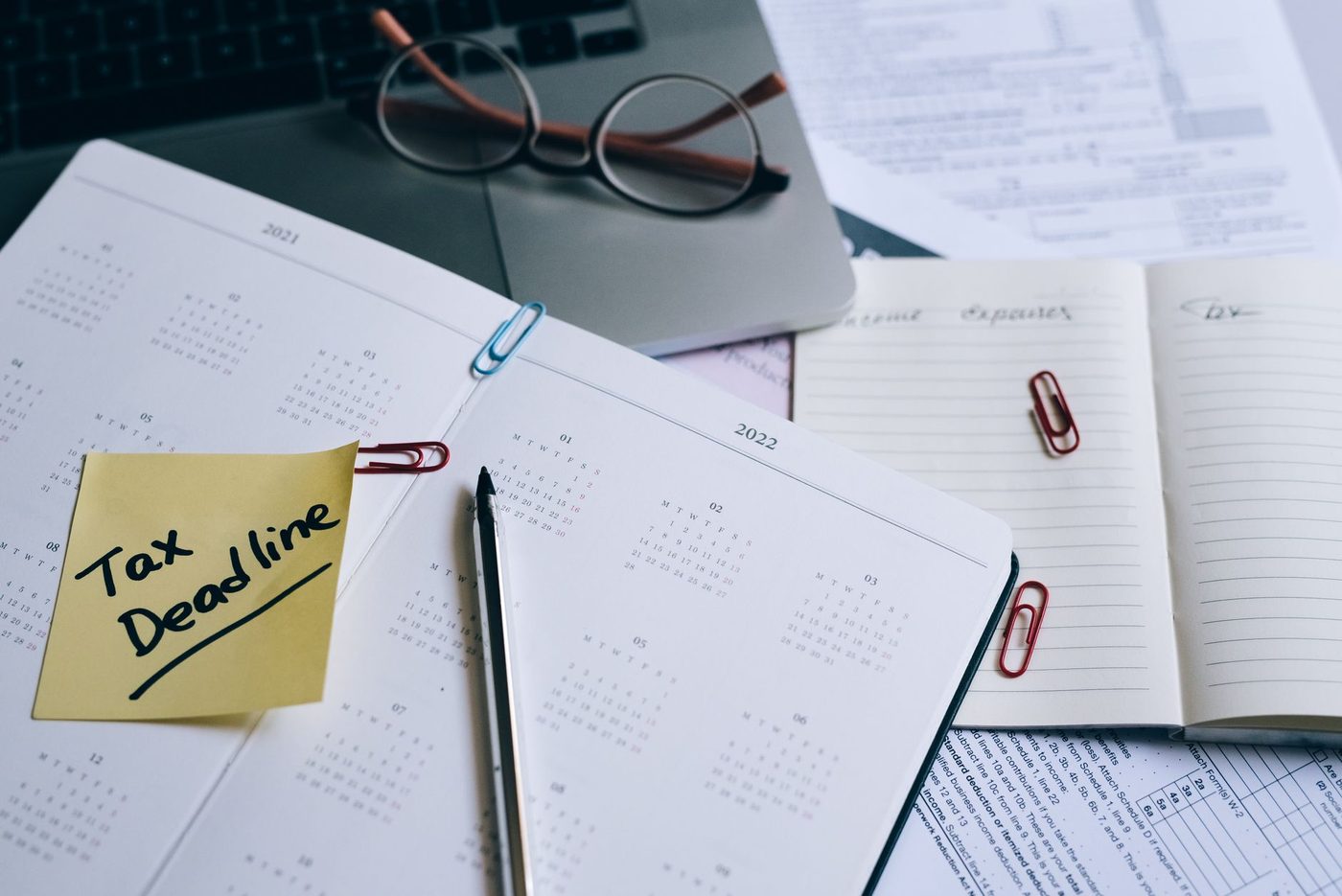 Calendar and paperwork on a desk with a pen and reading glasses