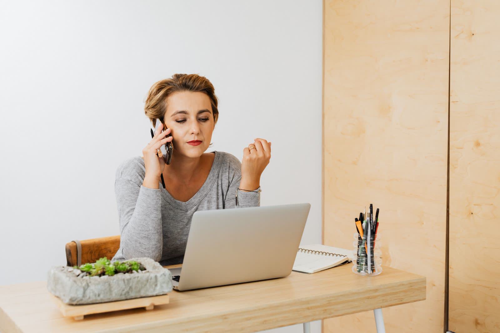 Woman taking a call at a bright white desk with a laptop