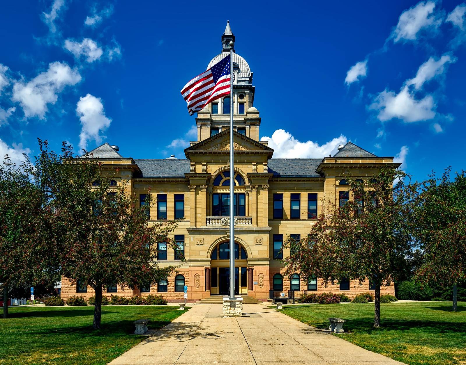 Historic county courthouse with a clock tower and an American flag on a bright day
