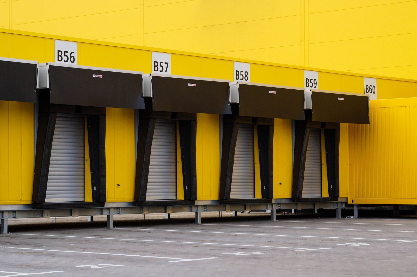 Row of yellow warehouse loading bays numbered B56 through B60 above their doors