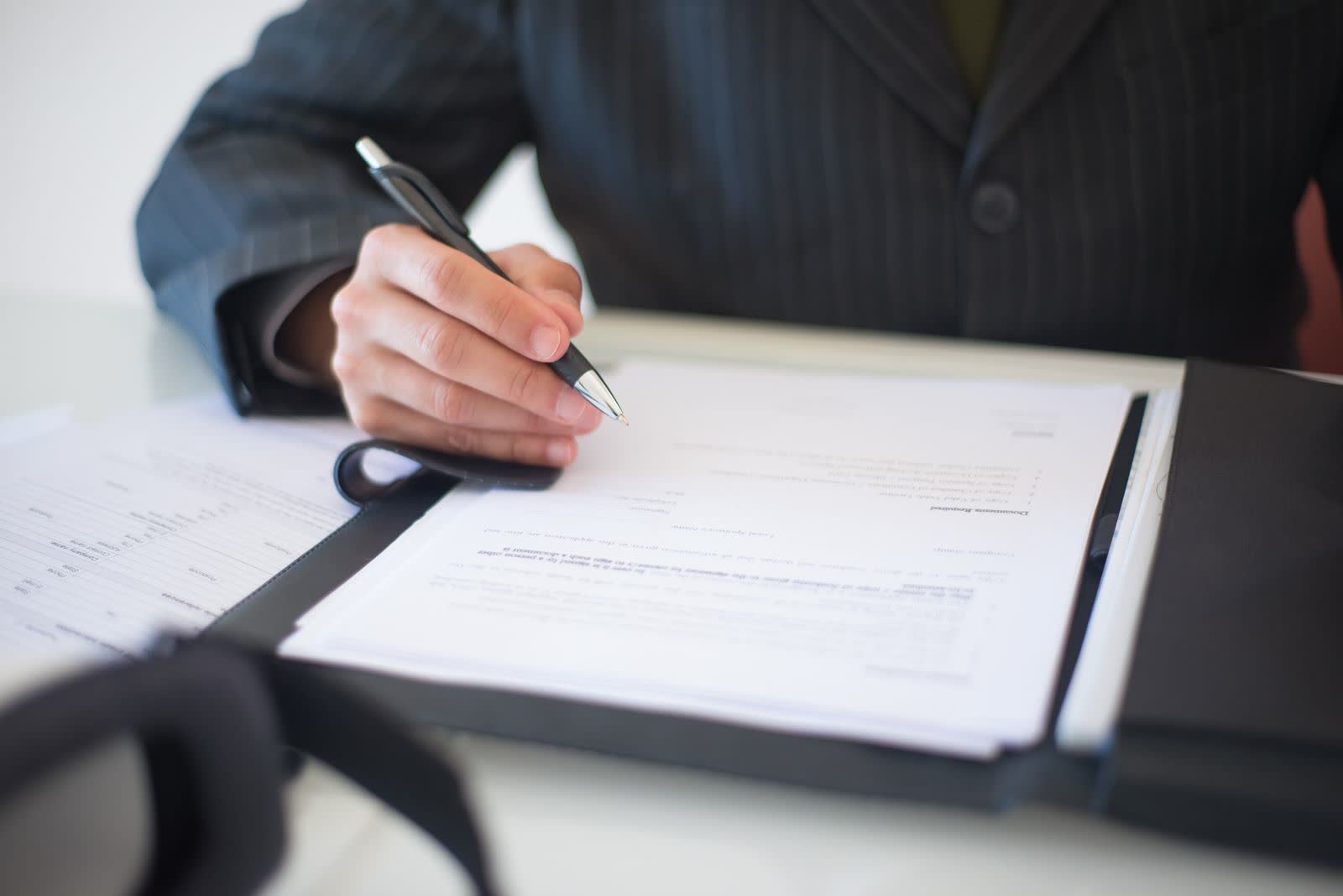 Close-up of a hand signing a business document with a pen