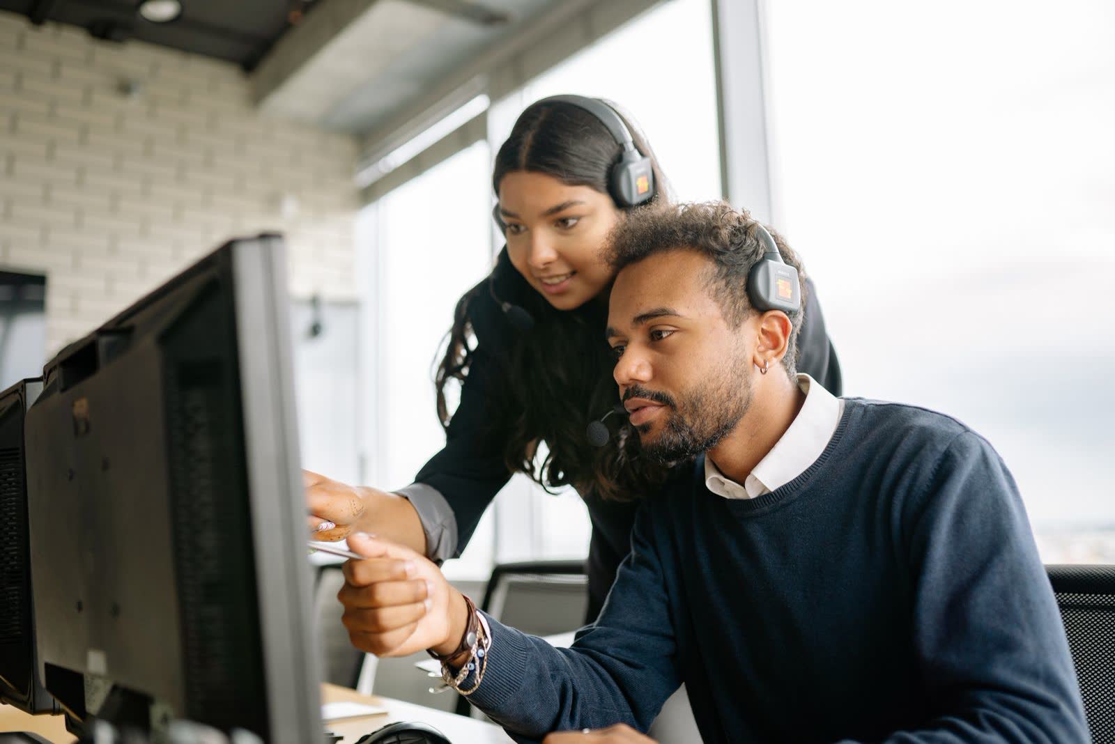 Support agent pointing at a colleague’s screen to help