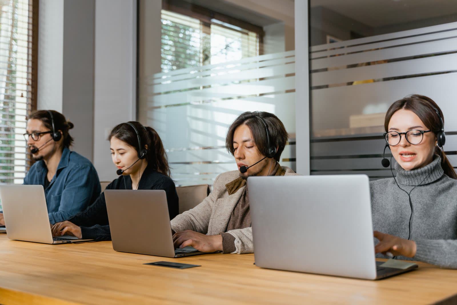 Support agents with headsets working at laptops