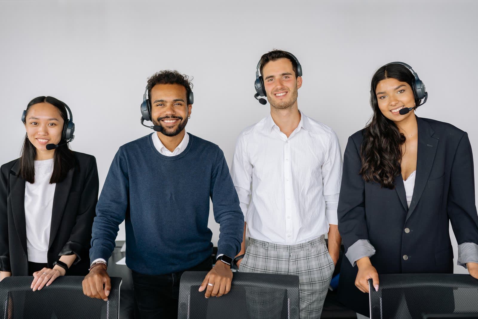 Smiling customer support team standing together with headsets