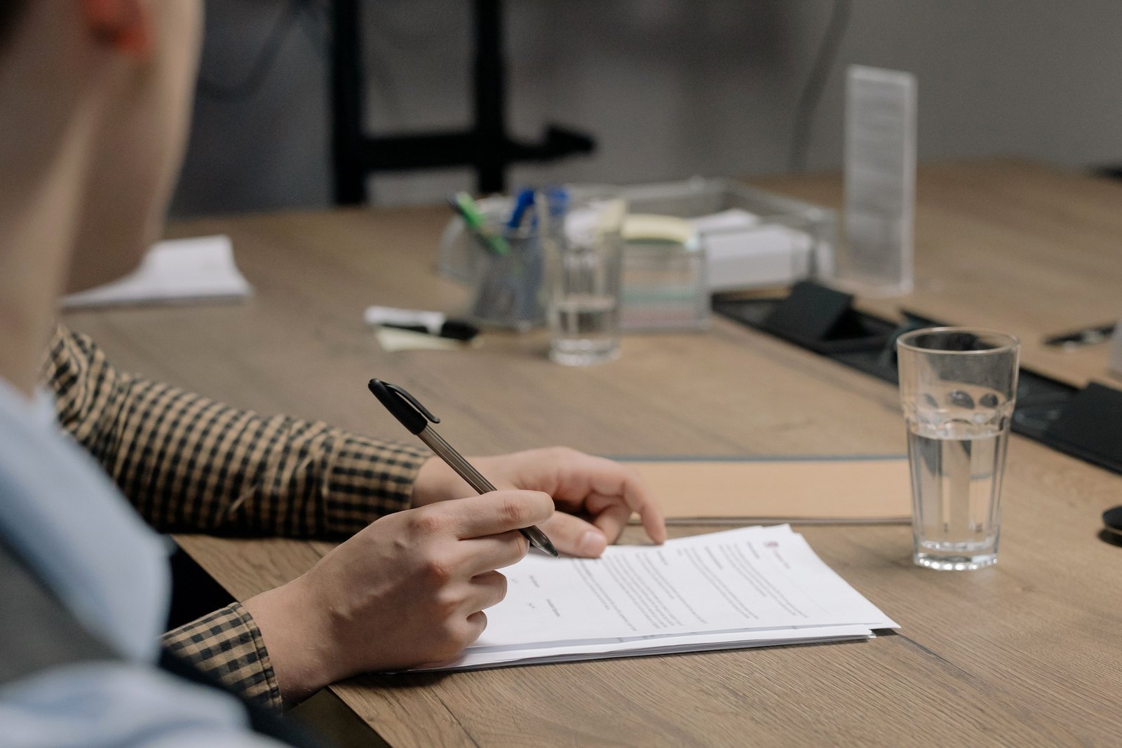 Person reading and annotating a printed document at a meeting table