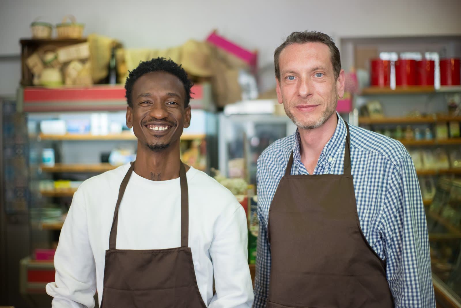Two smiling grocery store owners in aprons